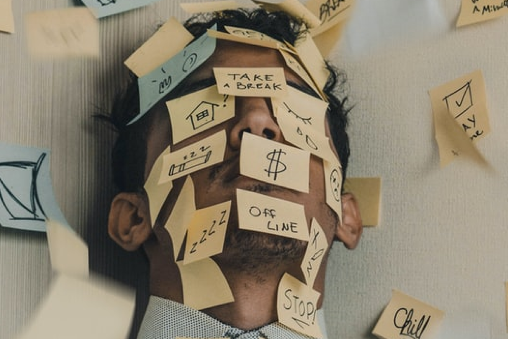 A man covered in post-it-notes with reminders on