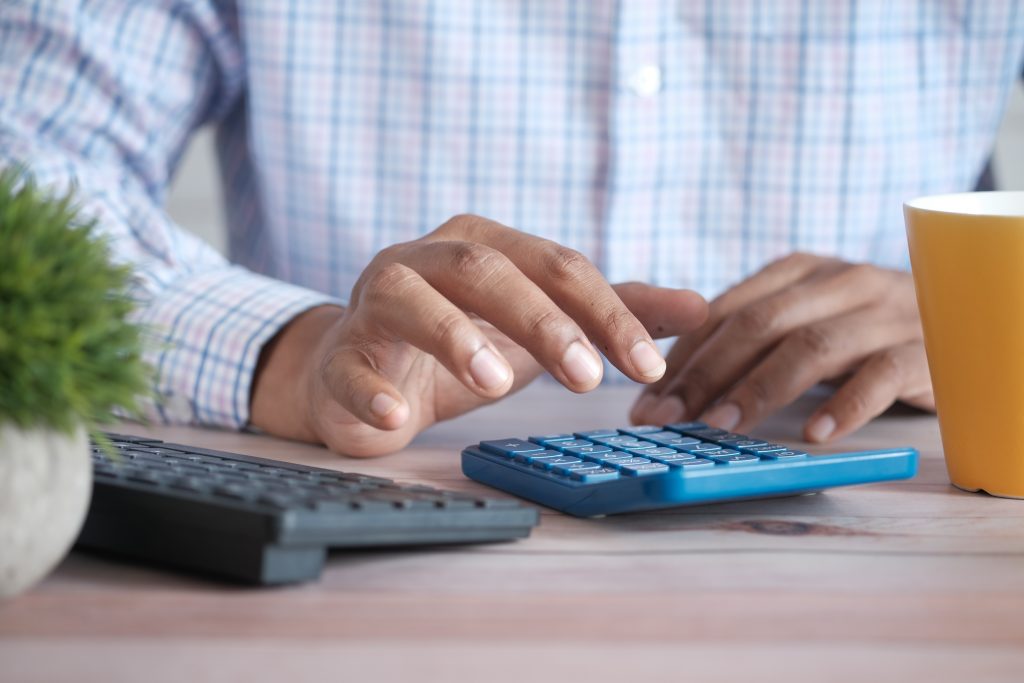 An Image of a man using a calculator to sort fees and funding